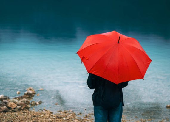 woman standing under red umbrella and pondering love and hurt