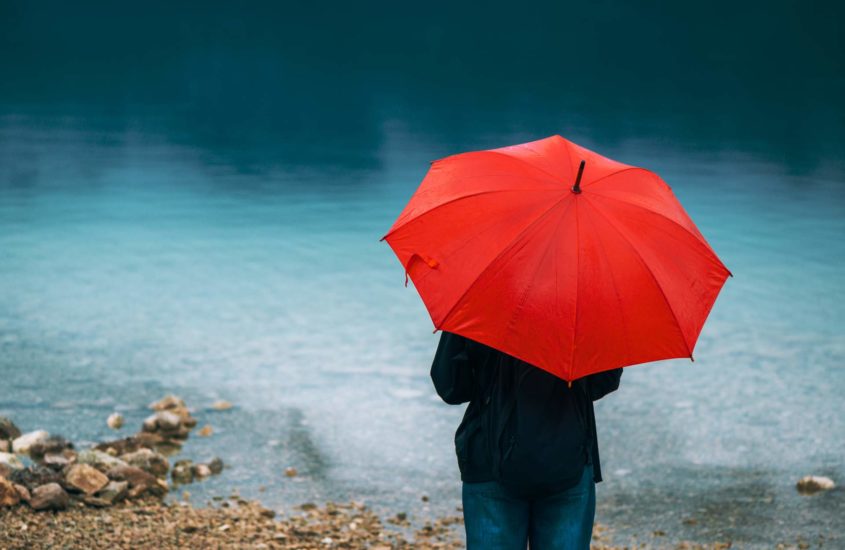 woman standing under red umbrella and pondering love and hurt