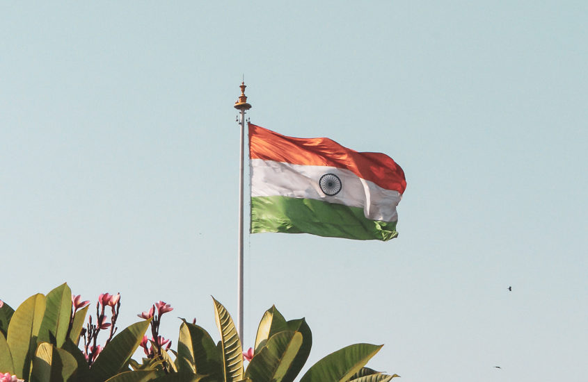 India flag against blue sky and some plants