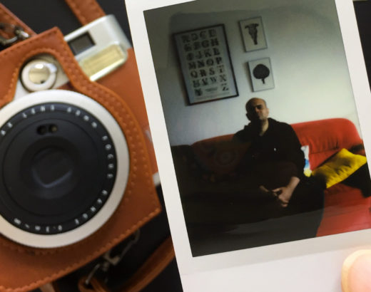 hand holding polaroid picture with camera in background