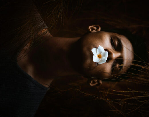 man with eyes closed and a flower in mouth depicting death or being asleep.